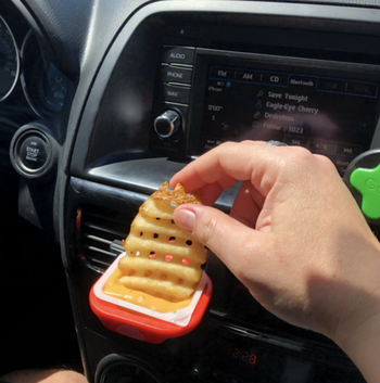 reviewer dipping waffle fry in sauce being held by clip
