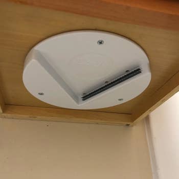 A reviewer photo of the lid opener mounted under the cabinet 
