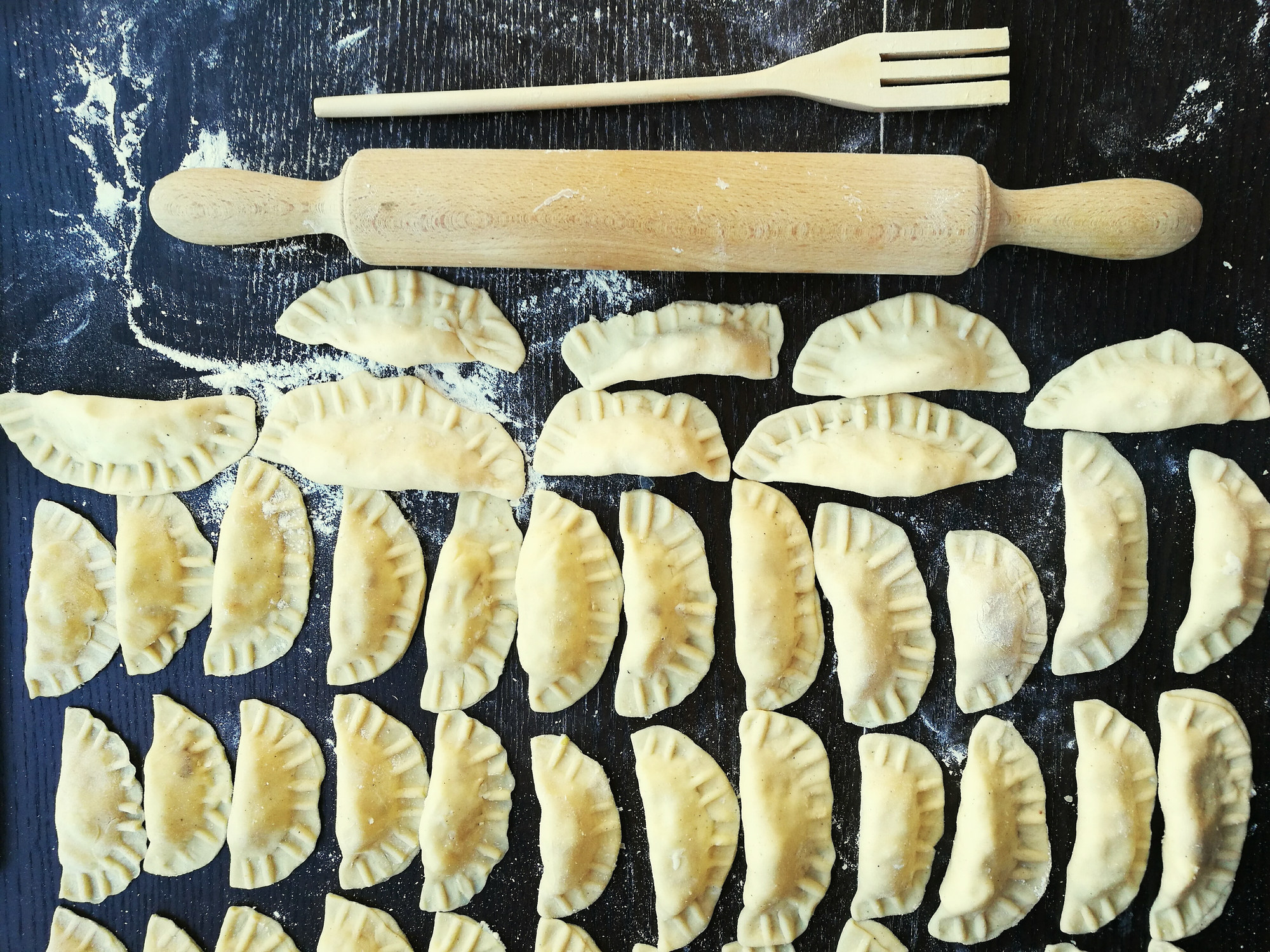 A tabletop of uncooked pierogis aka Polish dumplings.