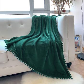 the blanket thrown onto a couch in emerald green