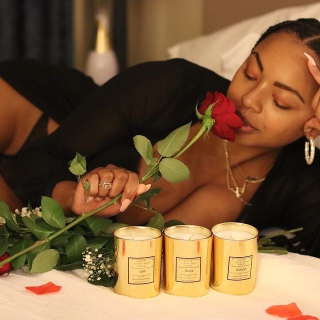 A person holding a rose behind three candles