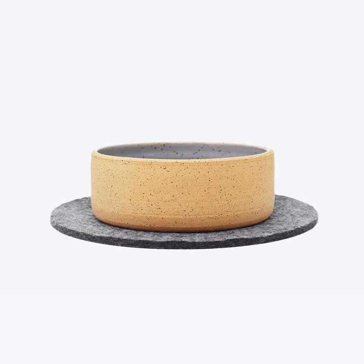 The gray circle mat with a bowl on it