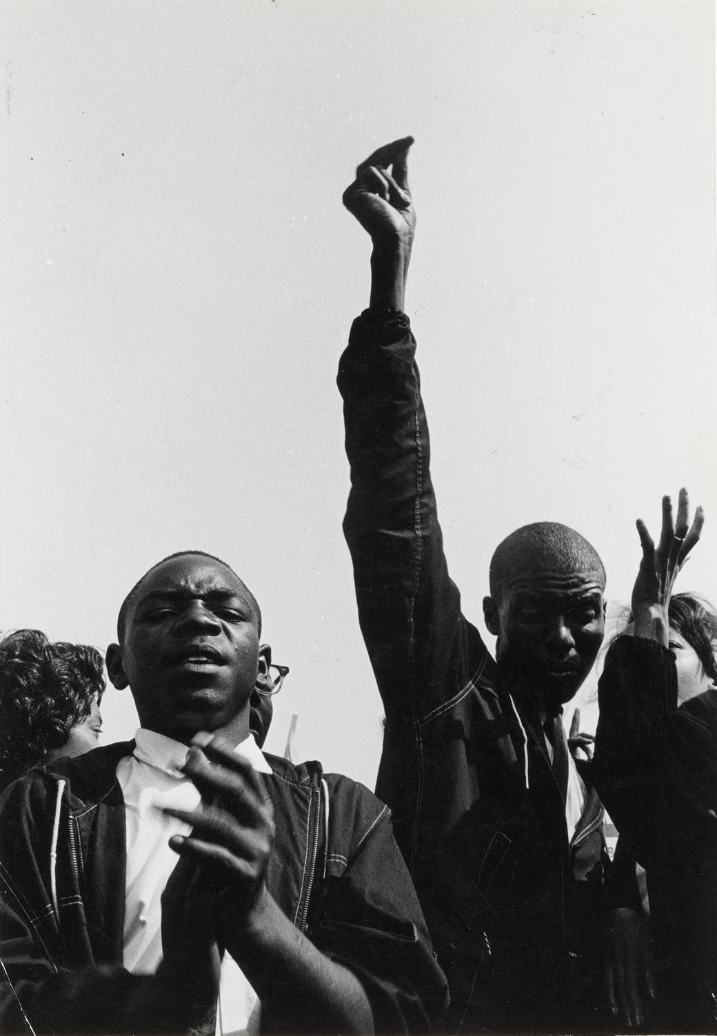 Men clapping and marching, one with his hand in the air