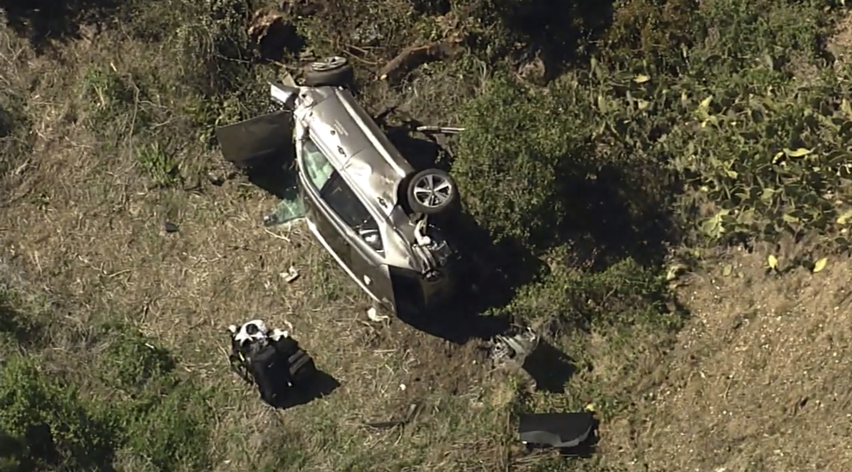 A damaged car rests on its side at the bottom of a hill in this aerial view