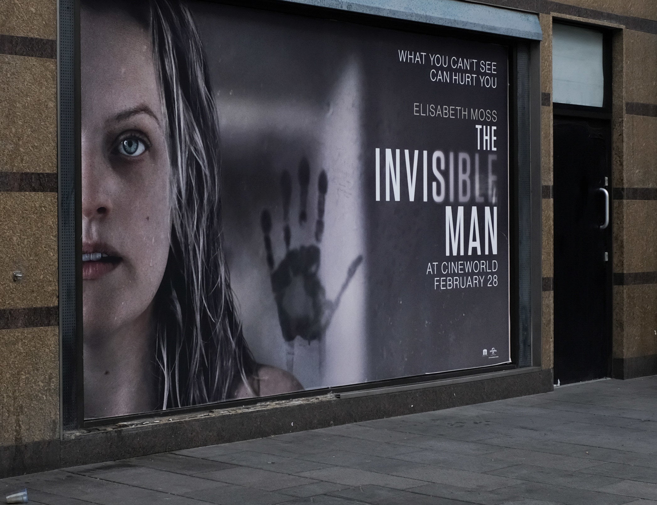 A large poster for &quot;The Invisible Man&quot; on the side of a wall featuring Elisabeth Moss and a handprint