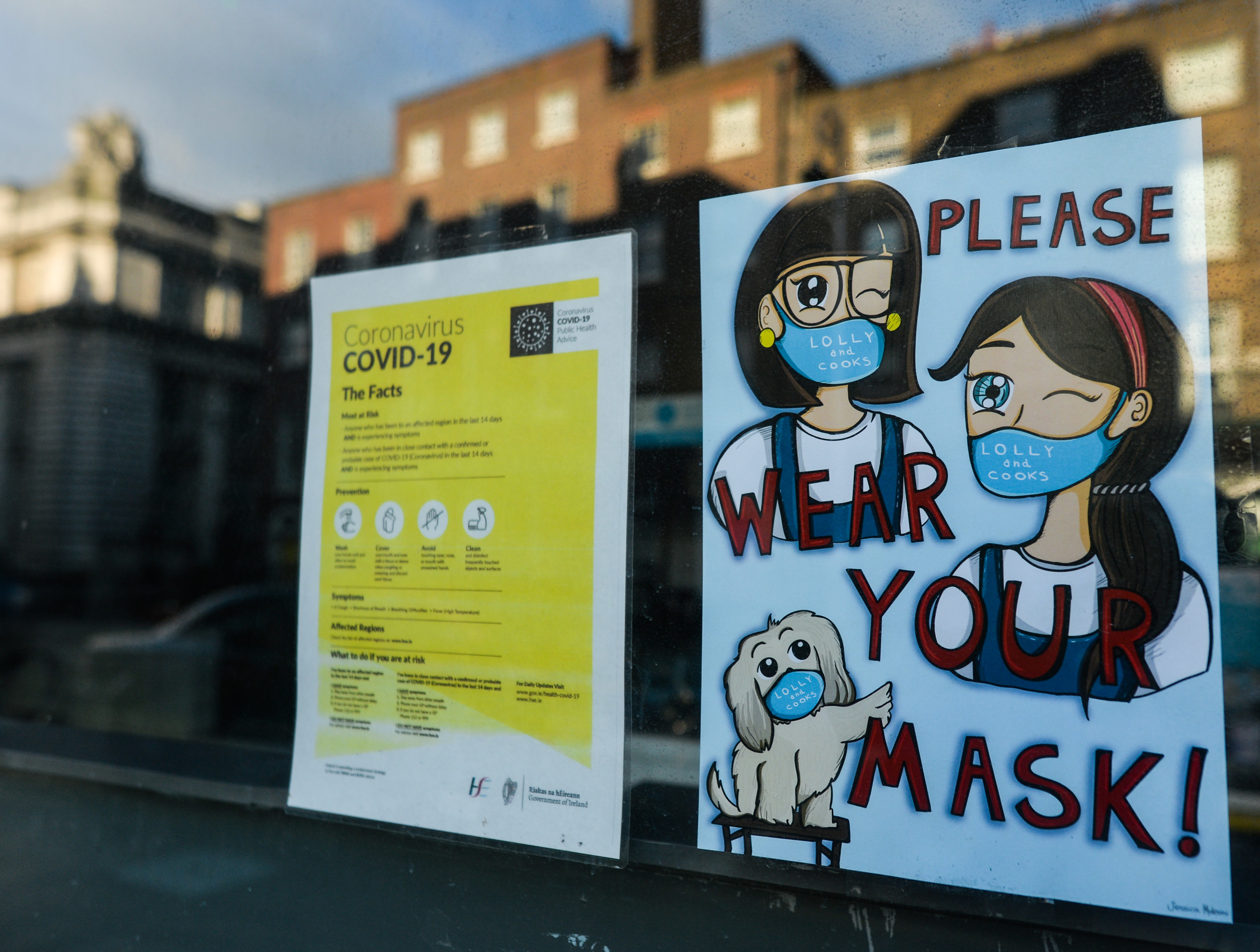 Two signs in a window telling people the facts about COVID-19 and encouraging people to wear masks