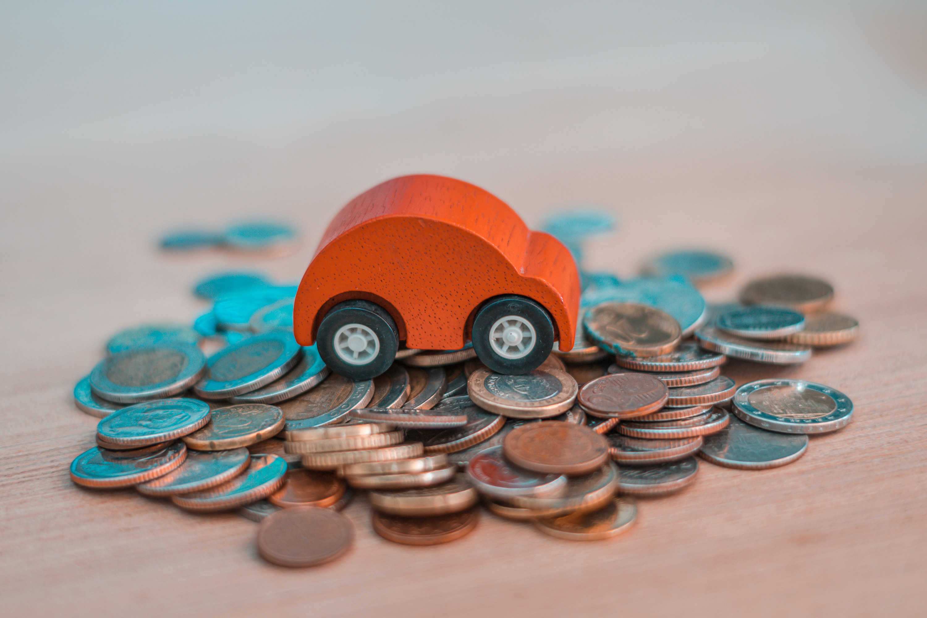 A wooden car on a pile of coins