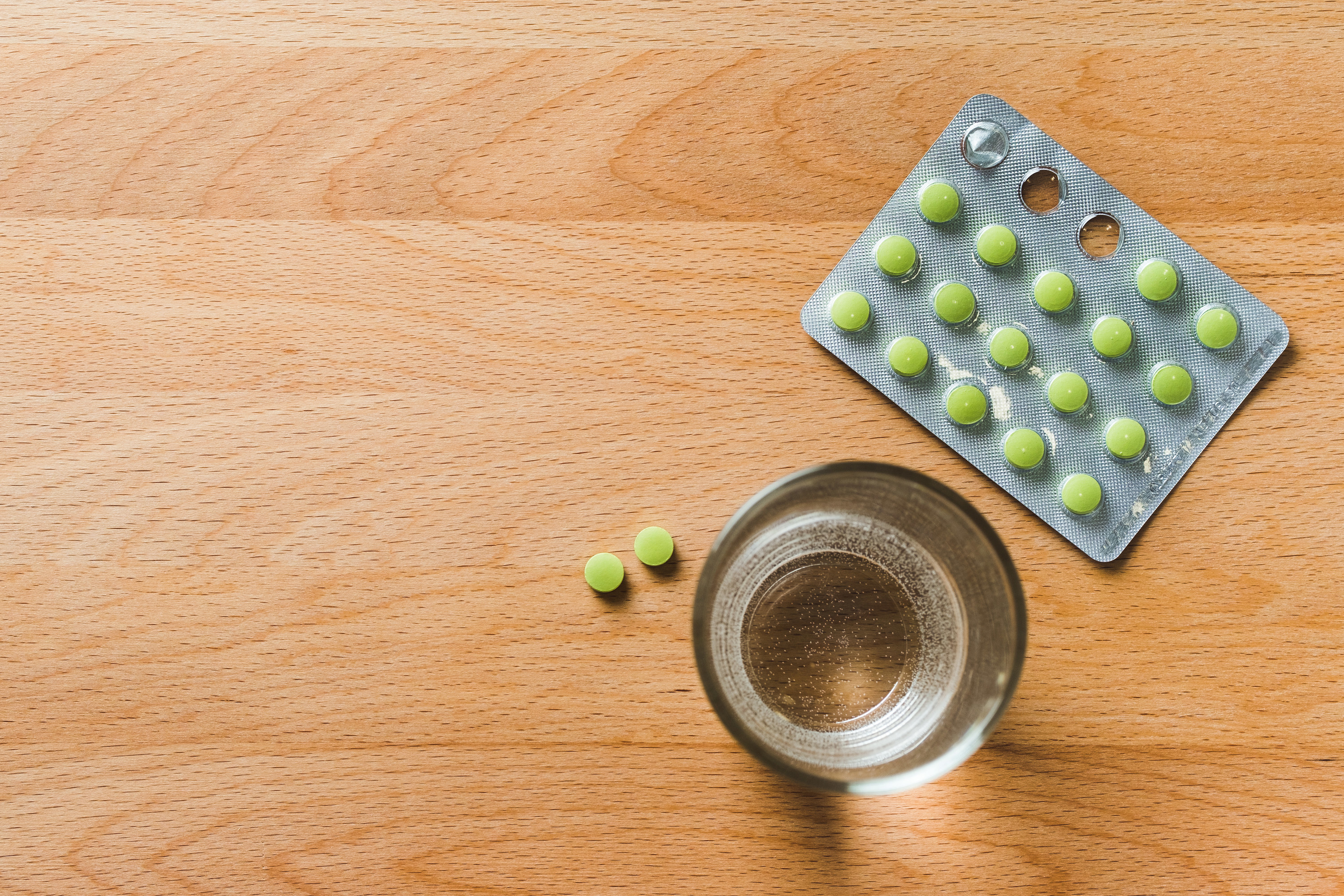 A glass of water and some prescription pills sitting on a table