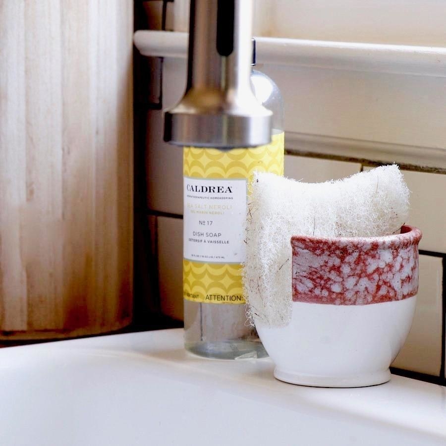 a white stoneware sponge holder with a marbled burnt orange ring