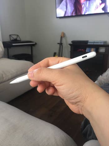 reviewer holding the white stylus pen, showing how it looks like an actual pen