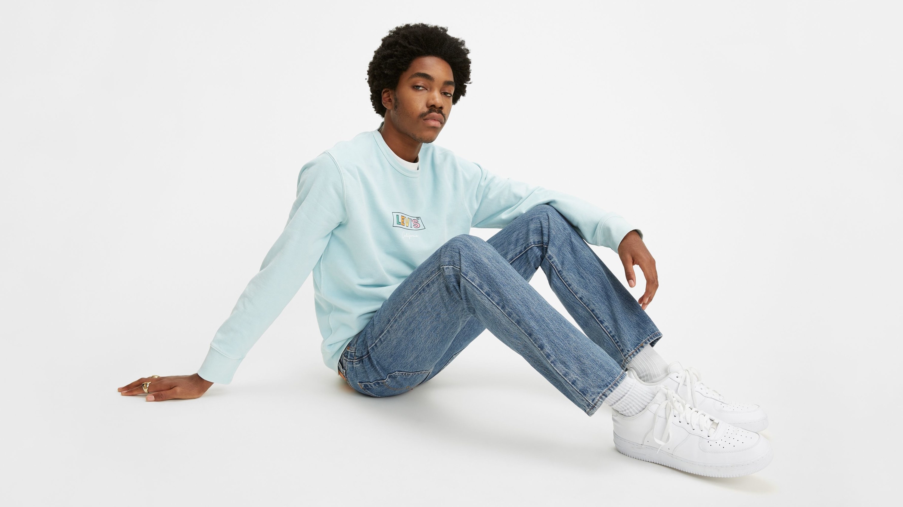 model wearing blue jeans while sitting down