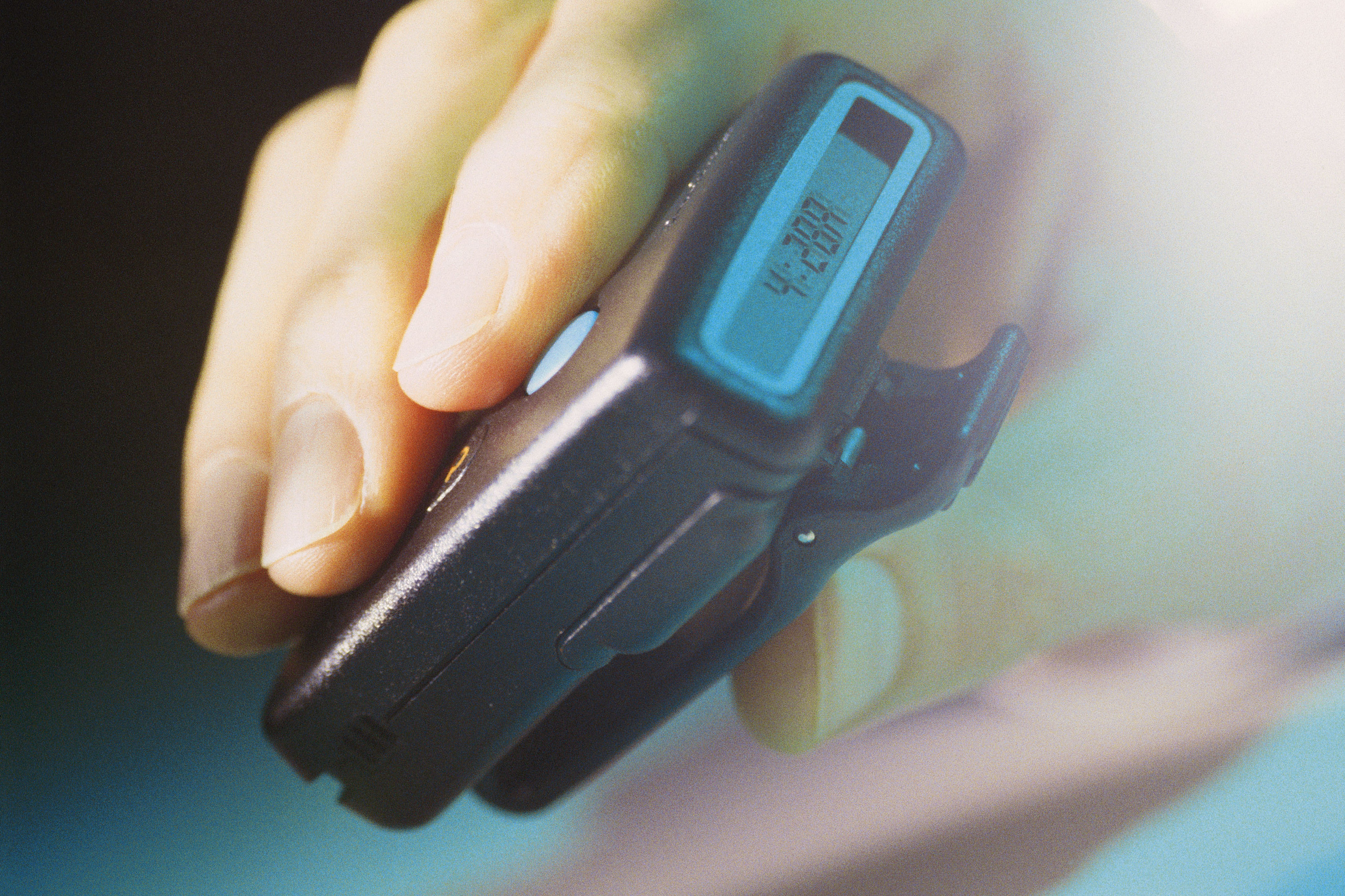 A hand holding a black pager
