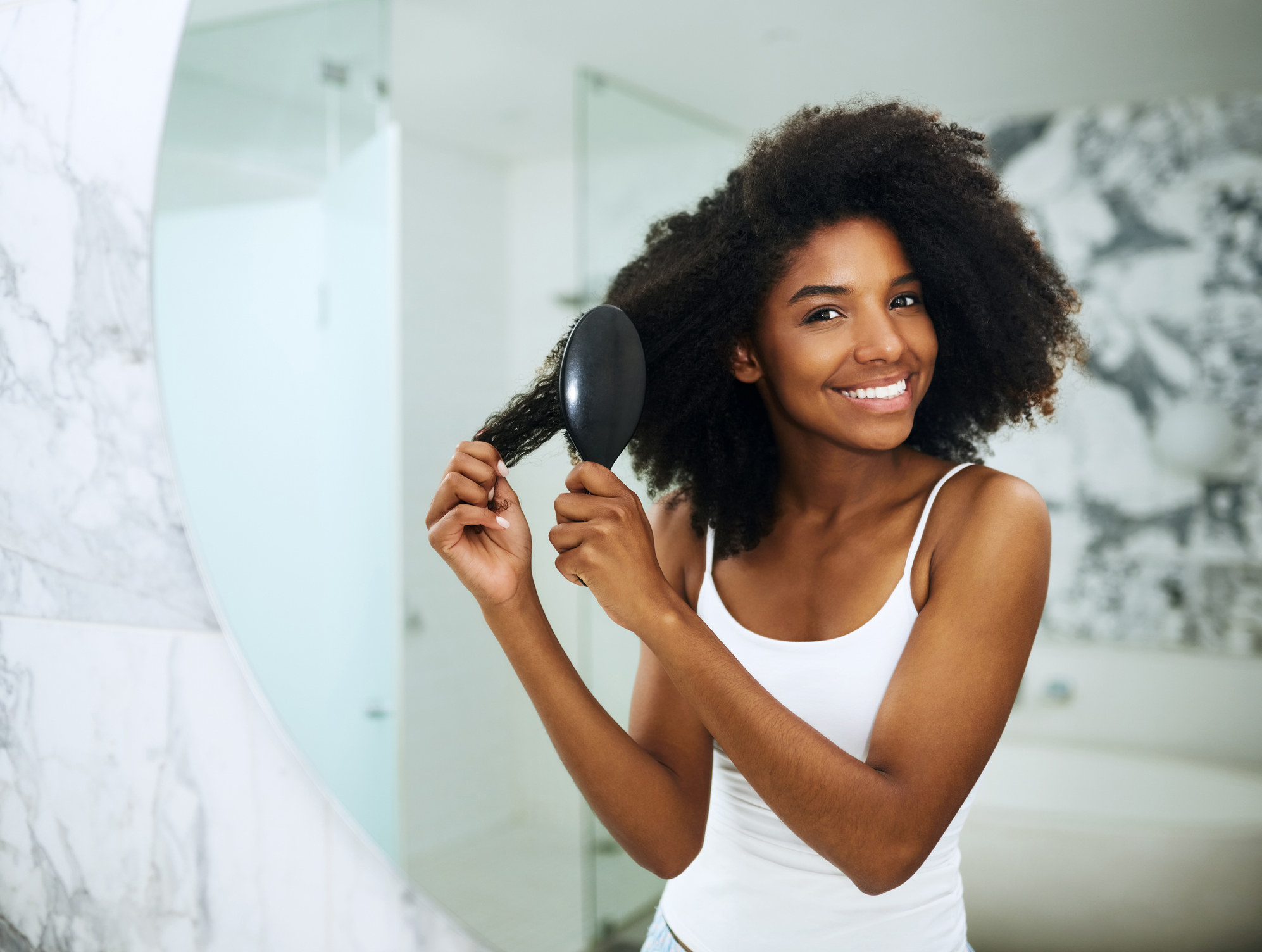 Portrait of a young woman brushing her hair at home