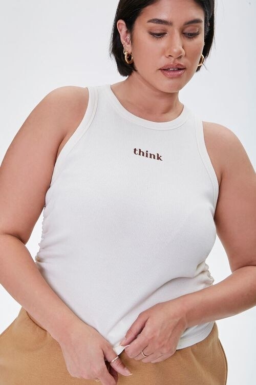 Model wearing white tank top which reads, &quot;think&quot;