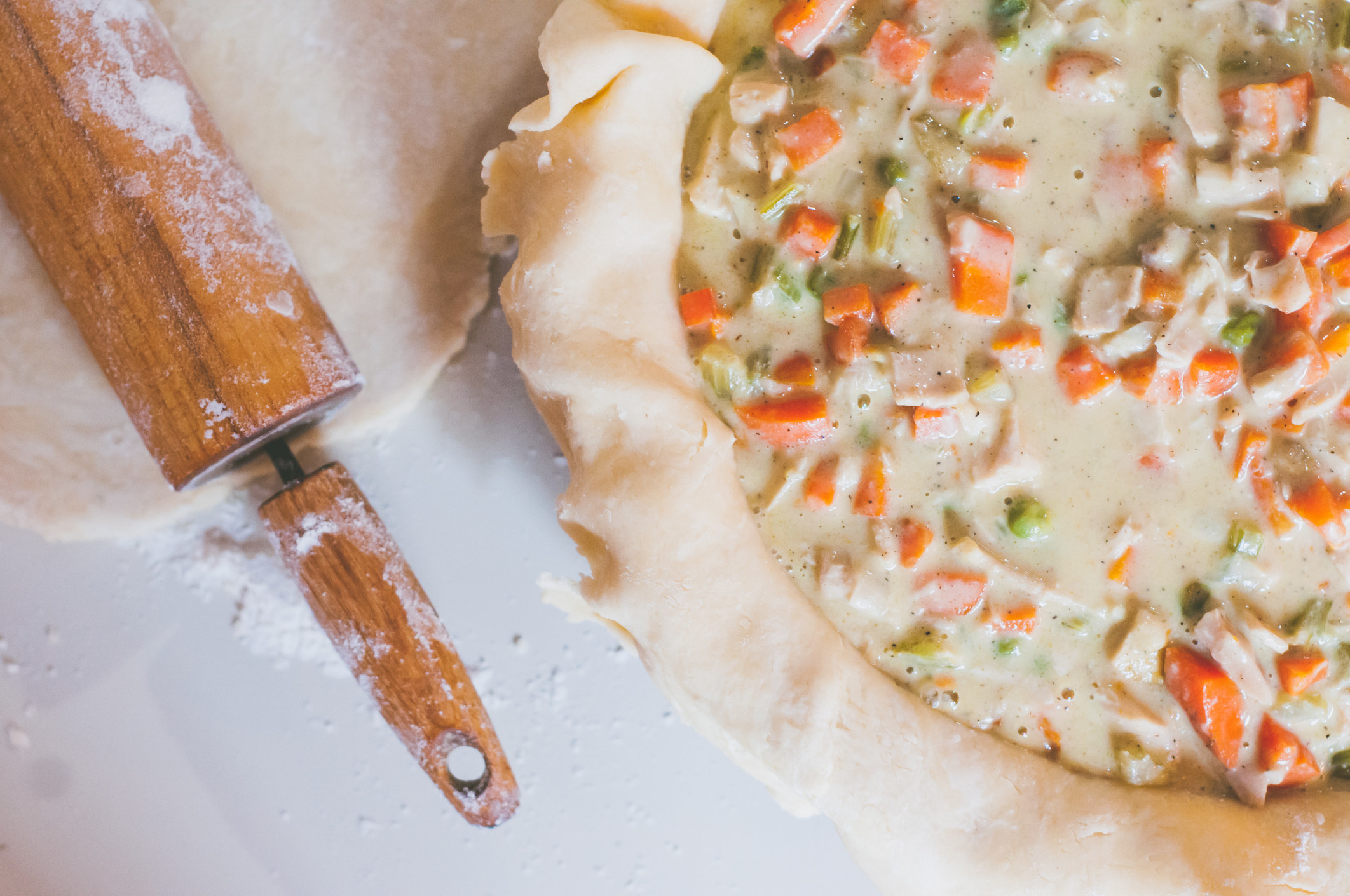 Uncooked chicken and vegetable mixture in a pie crust for chicken pot pie.