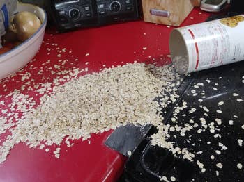 reviewer's photo of some dried oats that spilled out of a can onto the stove and counter but were blocked from falling between the crack because of the crack cover