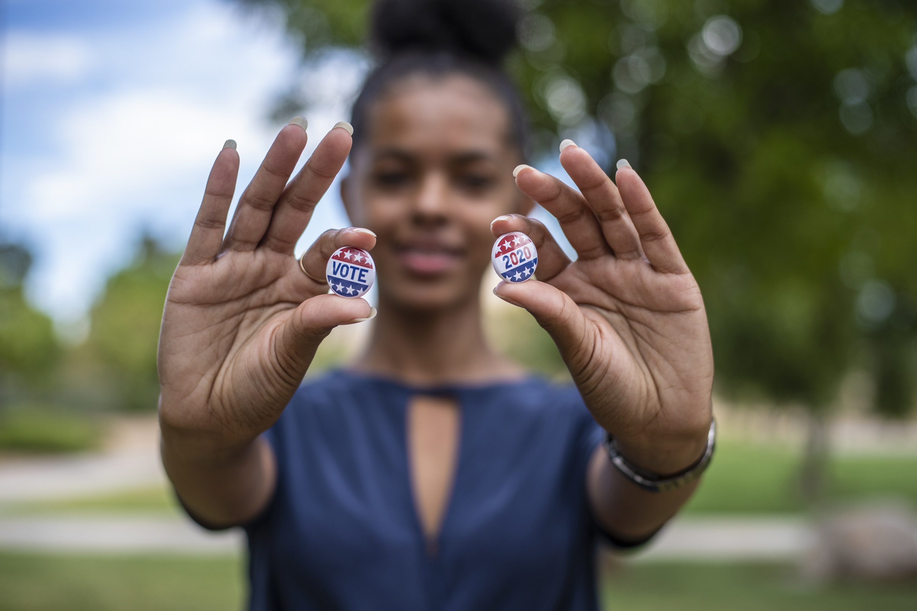 young person holding vote buttons