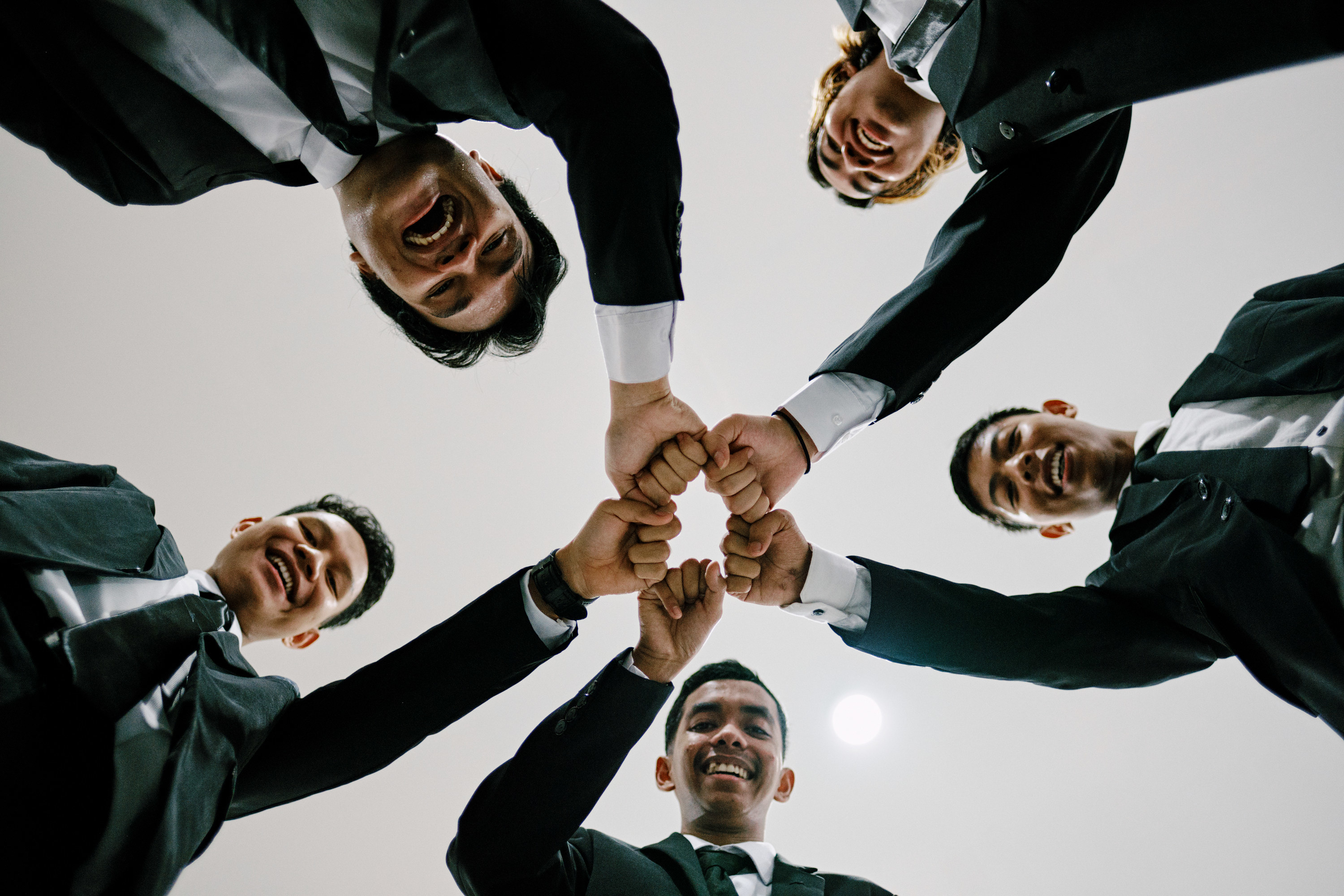 Circle of Asian American men putting hands together