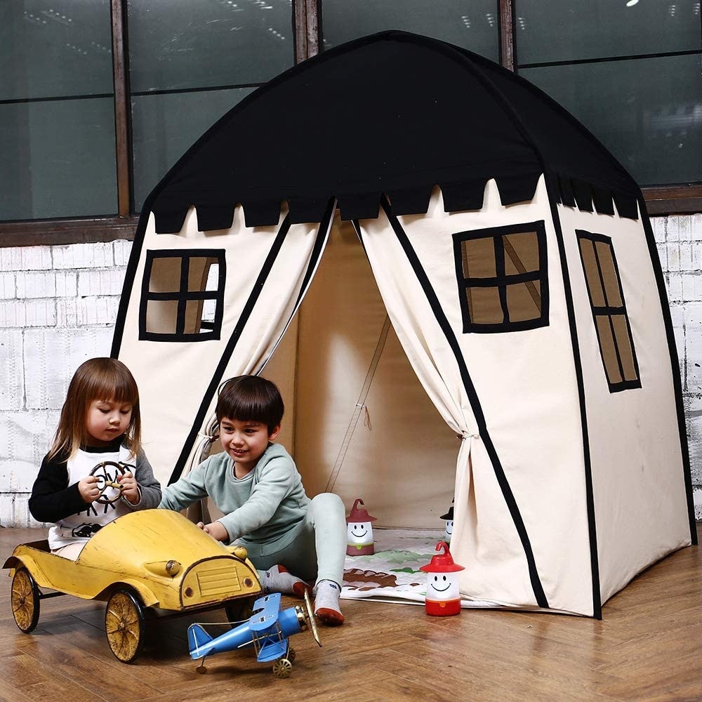 Children playing inside with a pop up play tent behind them 