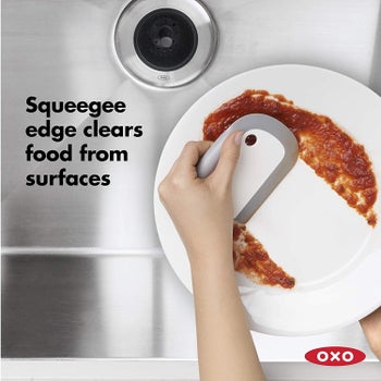 hands using the squeegee to scrape sauce off a plate with the text 