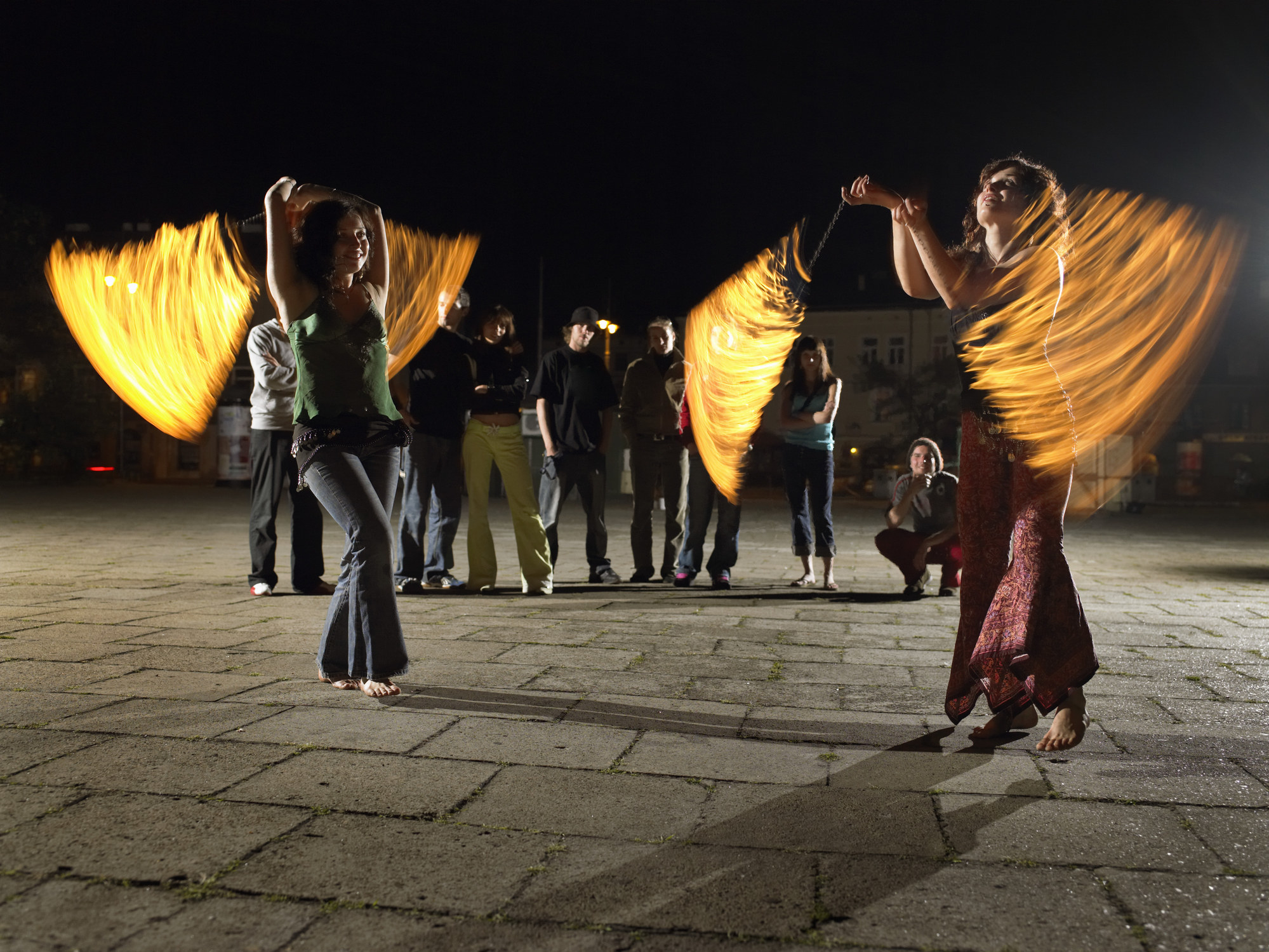 Women performing with fire batons on the street at night