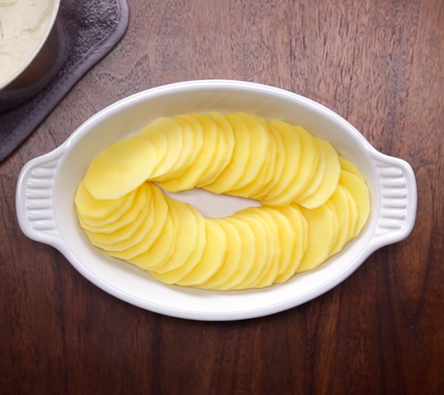 Thinly sliced potatoes in a casserole dish.
