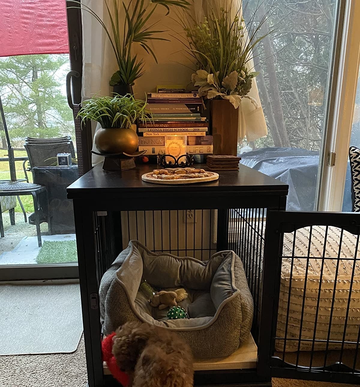 The crate with dog bed inside and decorative items on top