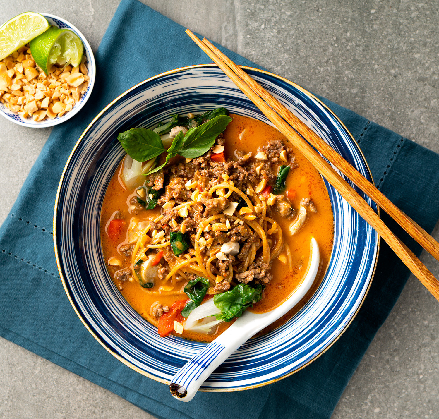 A top down view of a bowl of curry beef ramen with bamboo chopsticks on the bowl