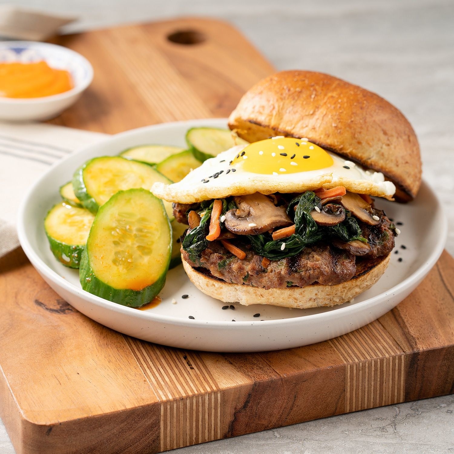 A Korean-spiced burger patty topped with a runny fried egg and served with a cucumber salad