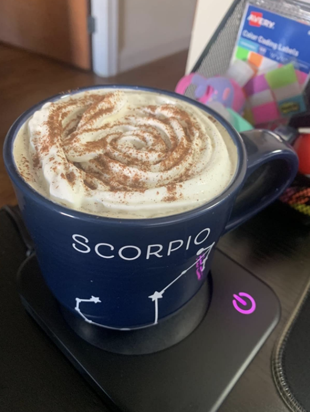 Scorpio coffee mug on the plain black warmer on a desk