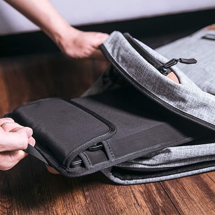 A person putting the sleeve into their backpack