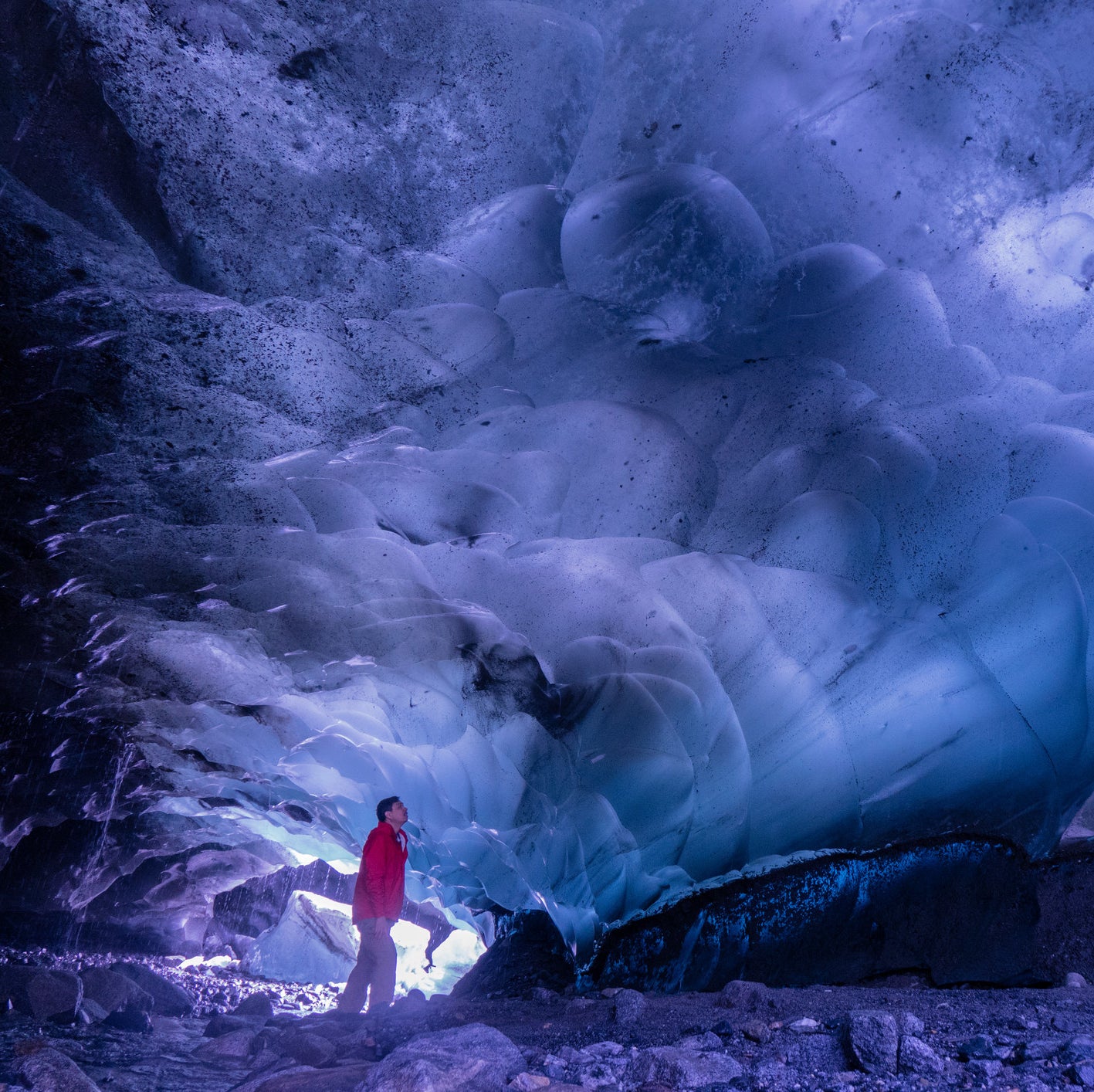 A man looking in awe at the shapes and color of the ice inside the ice caves. 