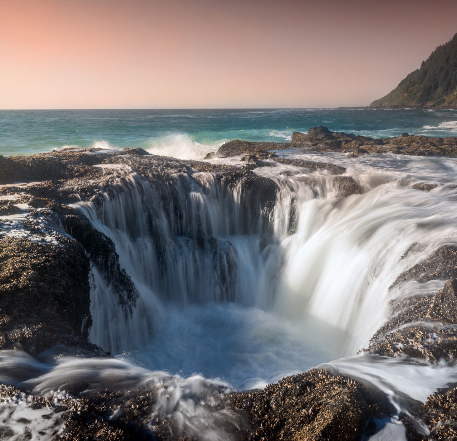 Water gushing into a hole on the rocky ocean shore