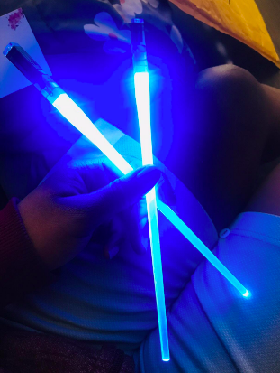Blue lightsaber chopsticks glowing in a dark room 
