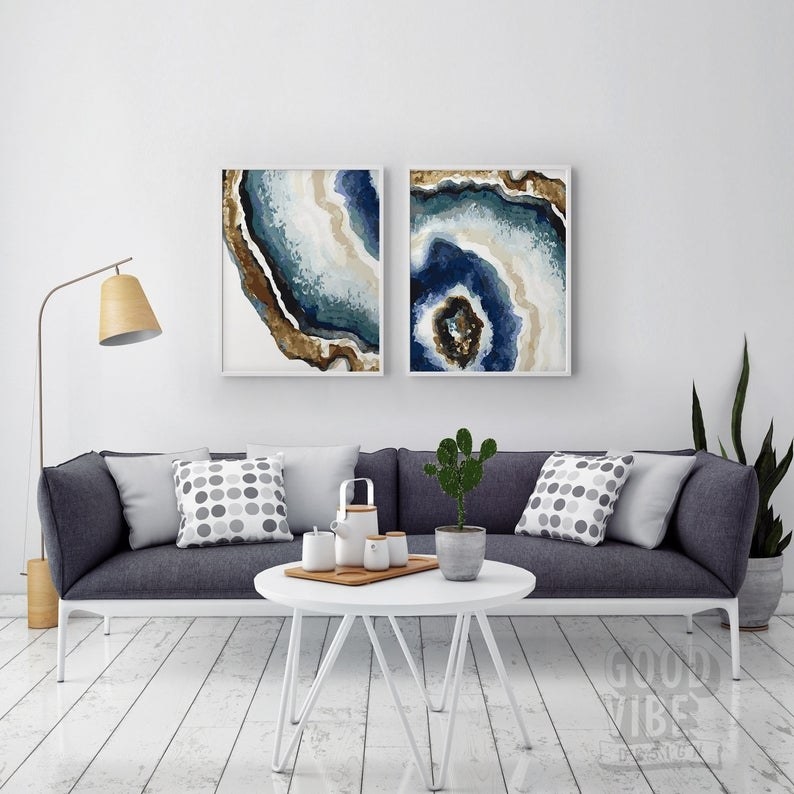 Two prints that make the single image of a gemstone slice on a wall above a couch 