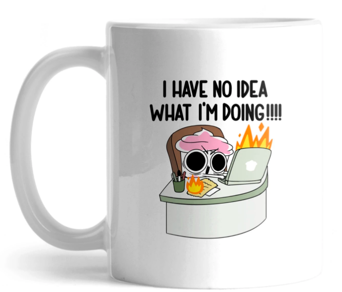 Classic coffee mug with illustration of a cupcake at a desk with their laptop and notes on fire. The worlds "I have no idea what I'm doing!!" are above the image.