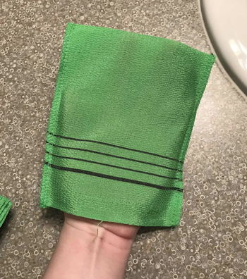 reviewer photo of user holding up green exfoliating towel 