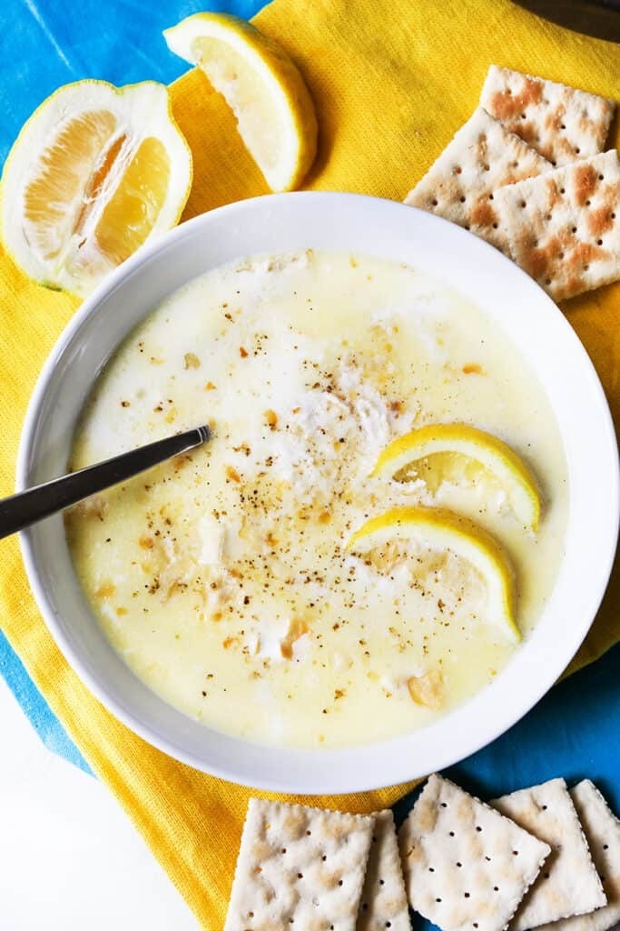 A bowl of crab soup with crackers on the side.