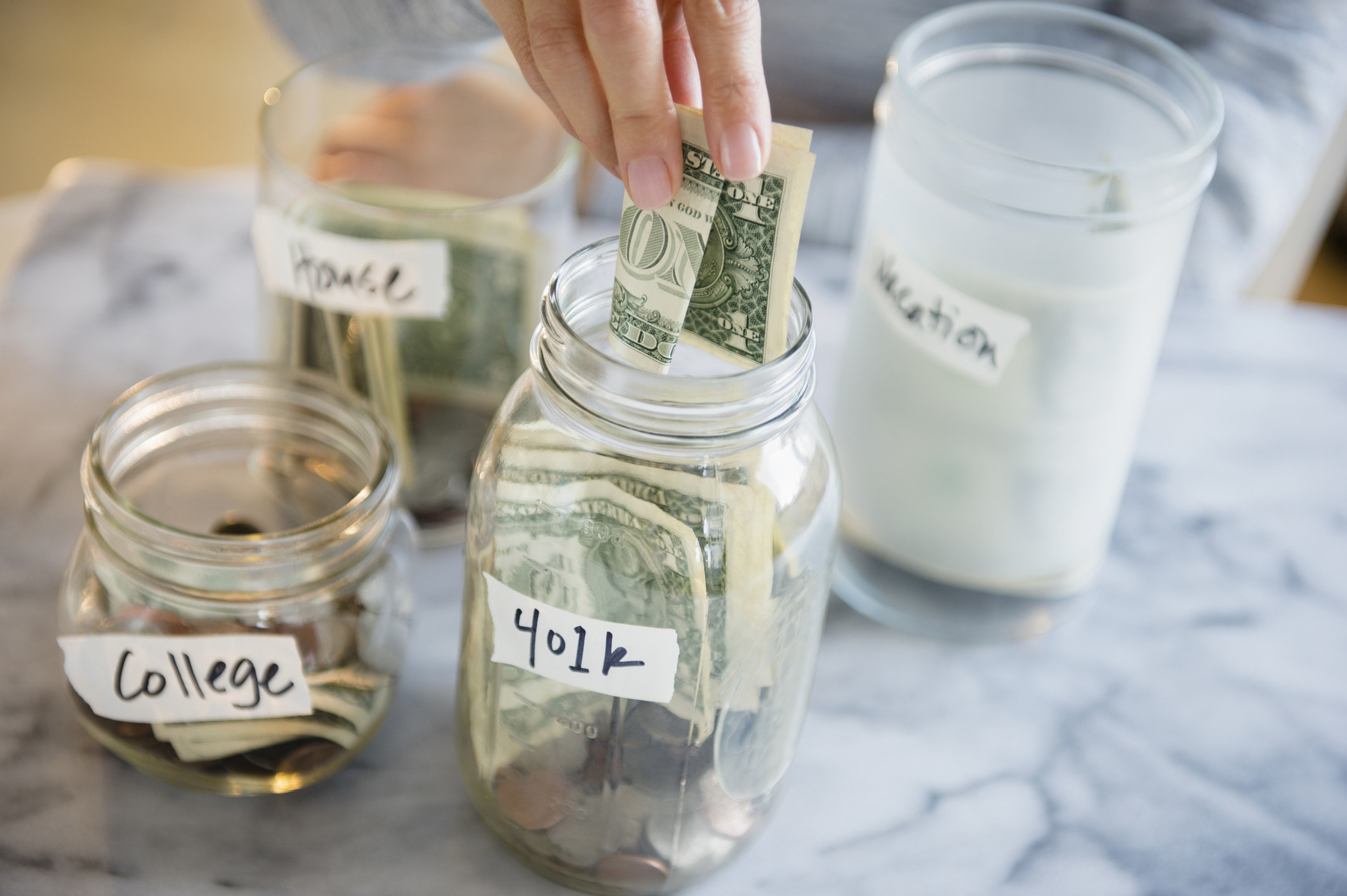 Person putting money into a 401(k) jar