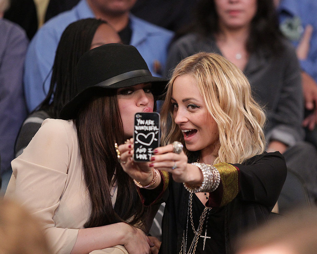 Khloe Kardashian (L) and Nicole Richie taking a selfie as they attend a game between the Sacramento Kings and the Los Angeles Lakers