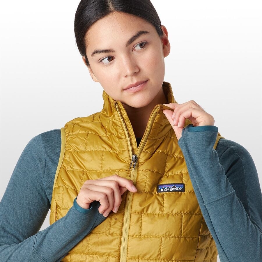 model wears gold Patagonia puffer vest over blue thermal shirt