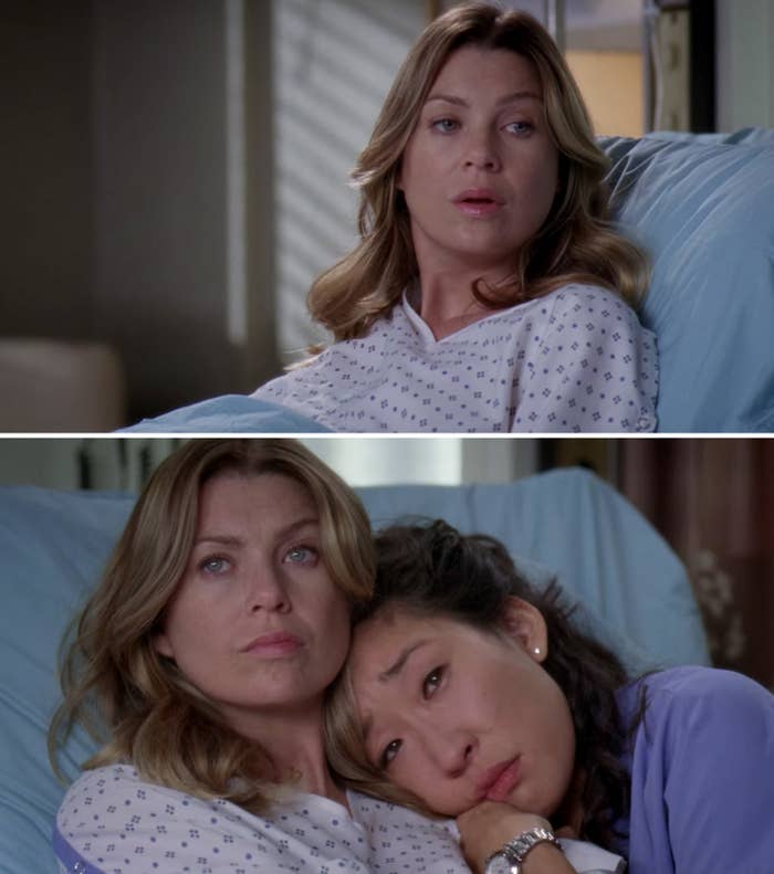 Meredith sitting in a hospital bed and Cristina putting her head on Meredith&#x27;s shoulder