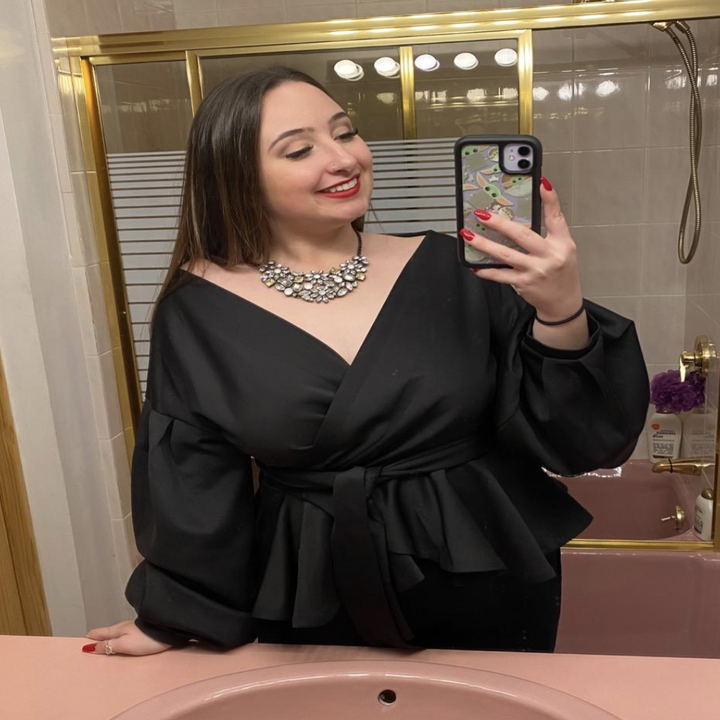 reviewer wearing the black top with a statement necklace 
