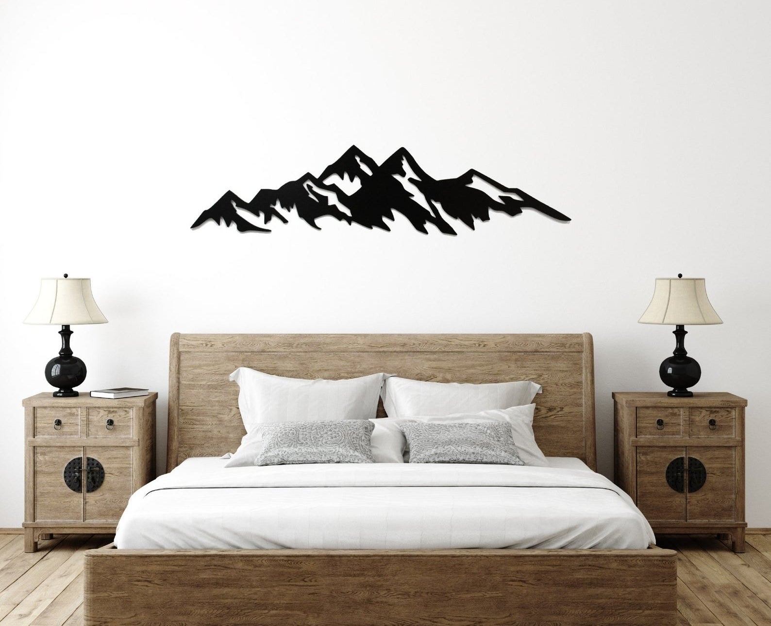 A minimalist black metal mountain range installed above a bed 