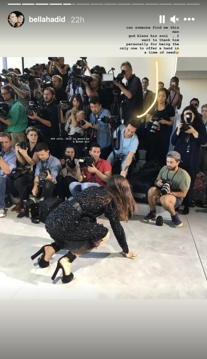 Bella falls to her knees in front of a row of photographers, one who is reaching out his hand