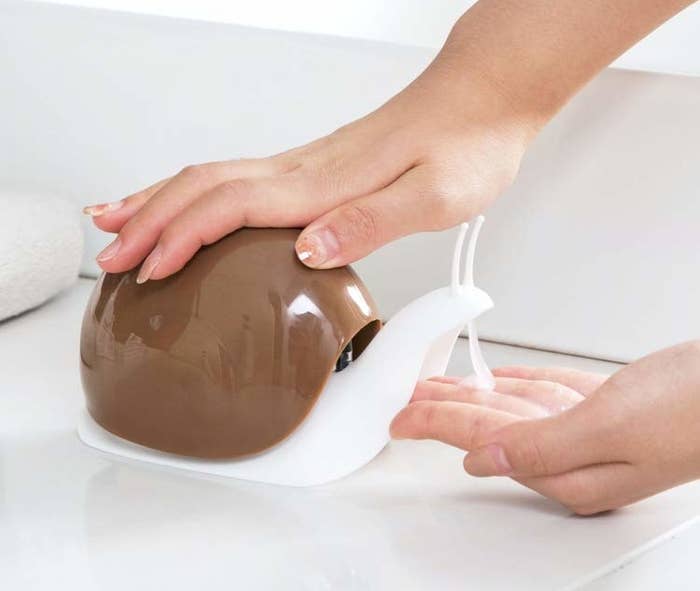A hand pressing down on the shell of the snail to take out soap.