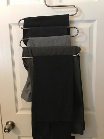 reviewer pic of five pairs of dress pants on the s-shaped hanger