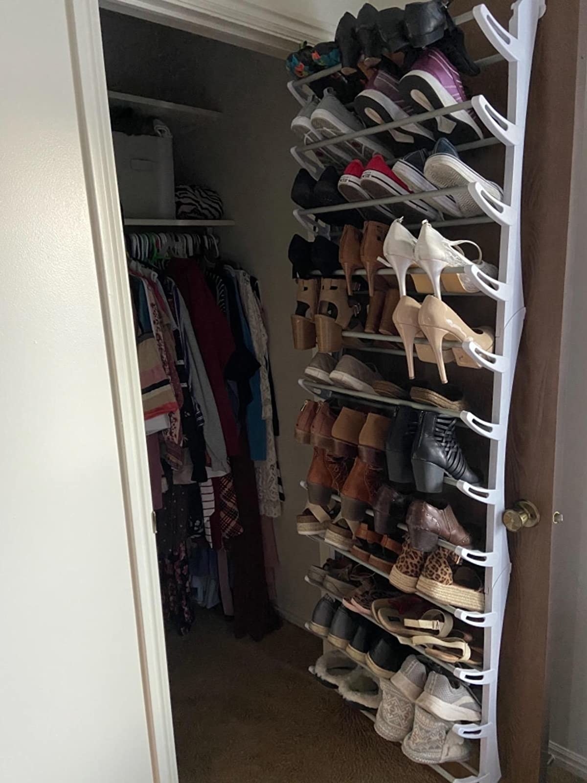 reviewer pic of the shoe rack on the back of a closet door filled with lots of pairs of shoes