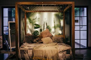 A bedroom with fuzzy pillows and fairy lights on the bed.