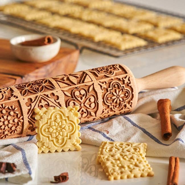 Square butter cookies with intricate vintage patterns made from the rolling pin beside them 
